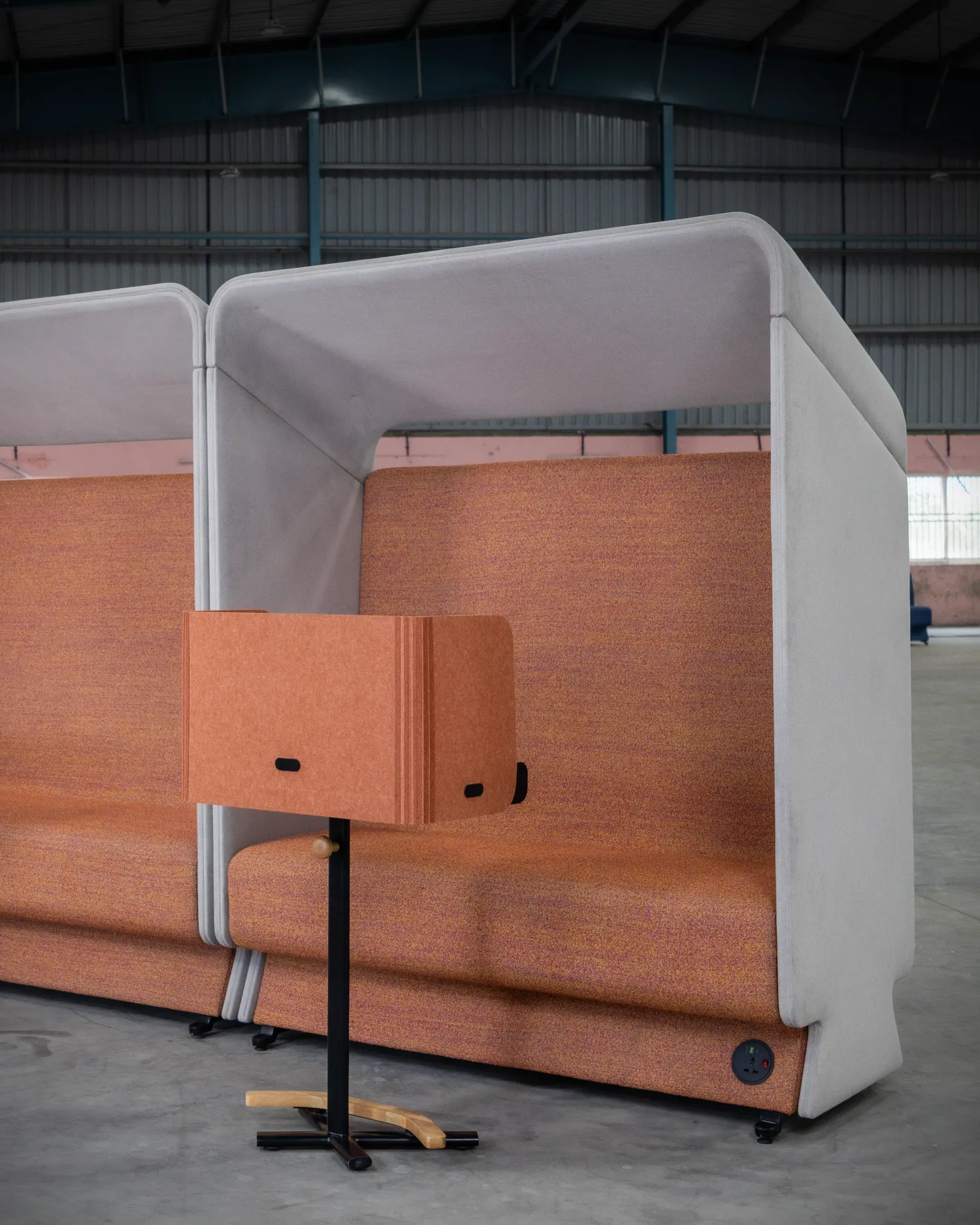 Attuny mono smart personal workstation with terracotta acoustic privacy hood in front of acoustic booth