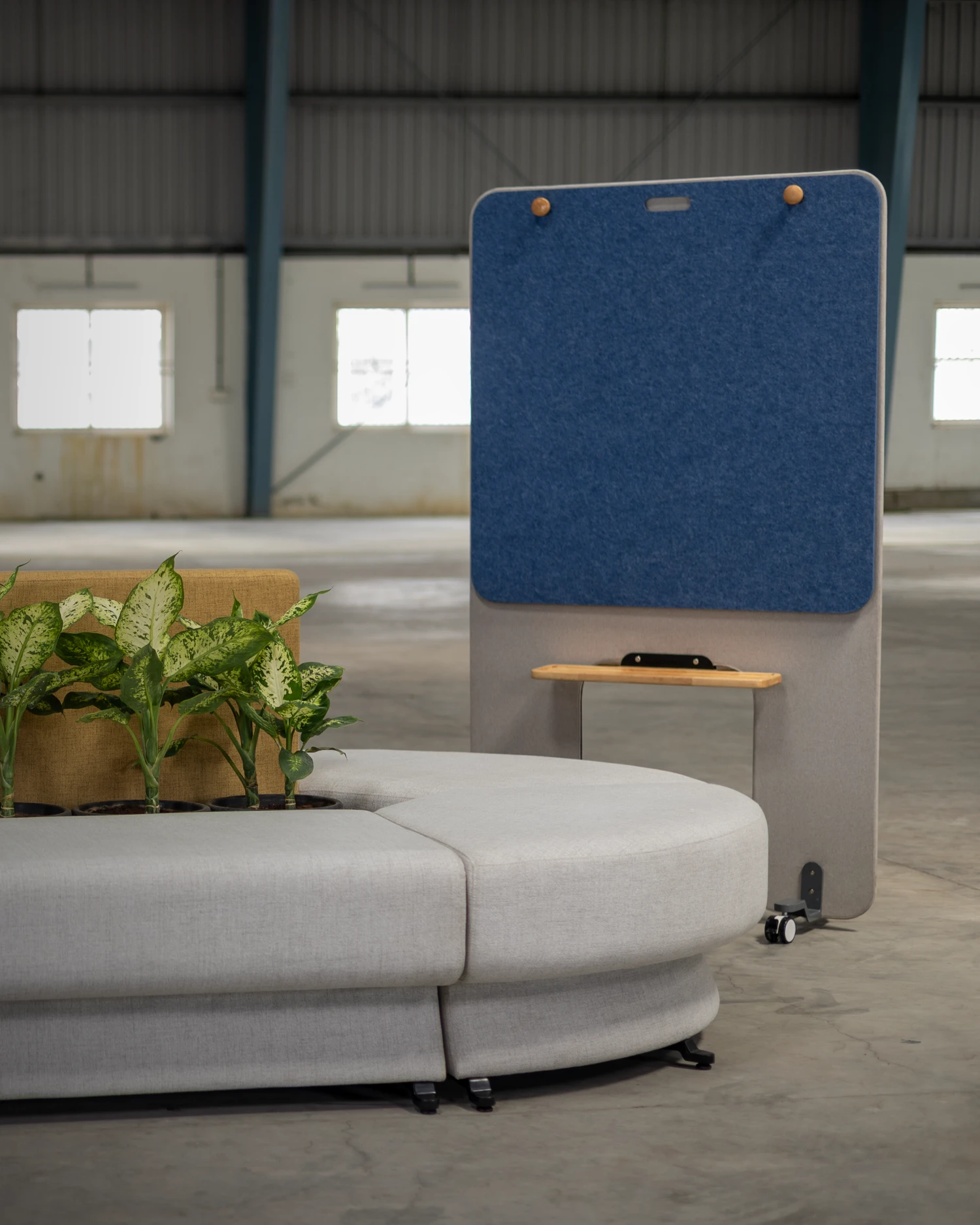 Attuny screen collaboration board with blue pinboard surface beside curved modular seating